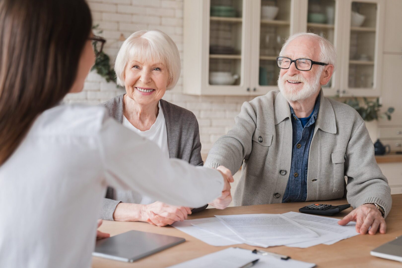 Elderly couple shaking hands with advisor.